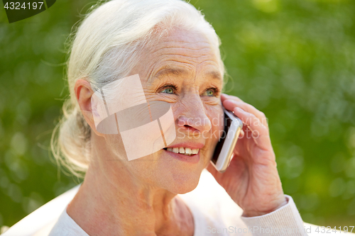 Image of happy senior woman calling on smartphone in summer