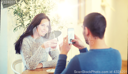 Image of man taking picture of woman by smartphone at cafe