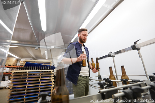 Image of men with bottles on conveyor at craft beer brewery