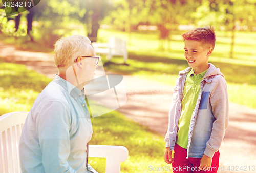 Image of grandfather and grandson talking at summer park