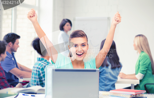 Image of happy student girl with laptop at school