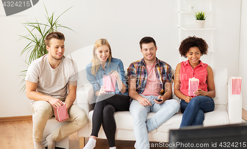 Image of happy friends with popcorn watching tv at home