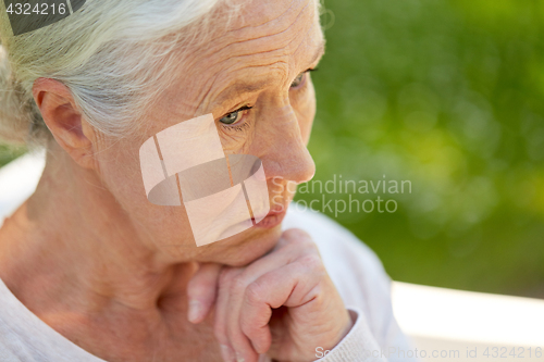 Image of sad senior woman sitting on bench at summer park