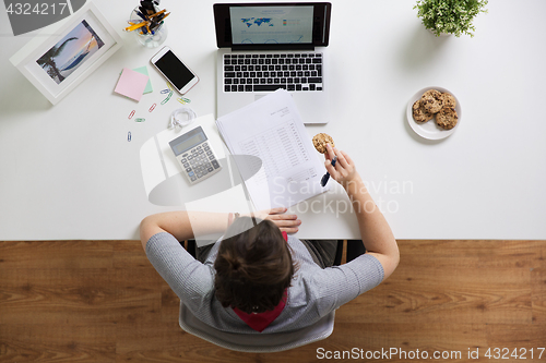 Image of woman with tax report eating cookie at office