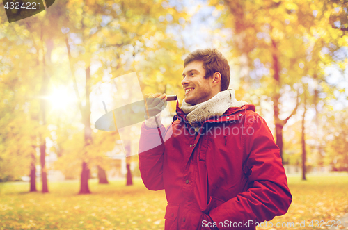 Image of man recording voice on smartphone at autumn park