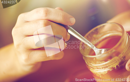 Image of close up of woman hands with honey and spoon
