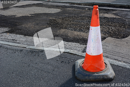 Image of Bright orange and white traffic cone on a sidewalk