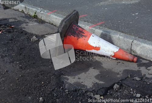 Image of Damaged traffic cone in gutter, road undergoing repairs