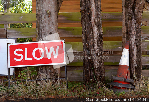 Image of SLOW traffic sign with broken orange and white traffic cones