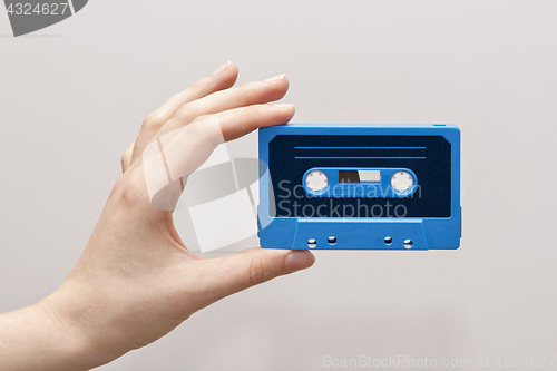 Image of hand holding blue cassette tape