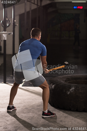 Image of man workout with hammer and tractor tire