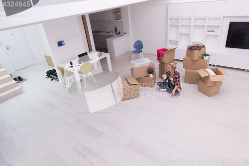 Image of woman with many cardboard boxes sitting on floor