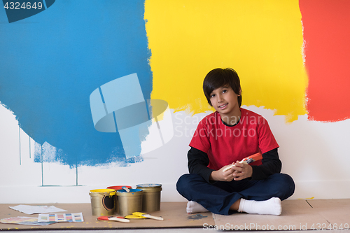 Image of young boy painter resting after painting the wall