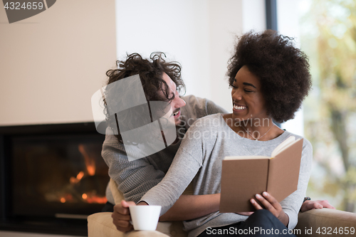 Image of multiethnic couple hugging in front of fireplace