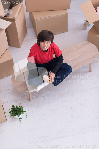 Image of boy sitting on the table with cardboard boxes around him top vie