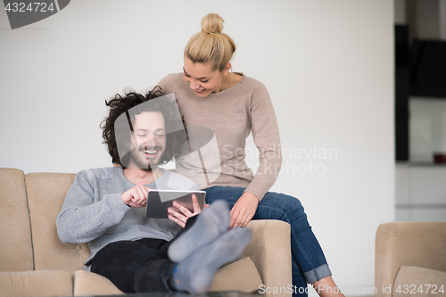 Image of couple relaxing at  home with tablet computers