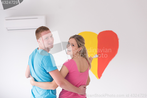 Image of couple are painting a heart on the wall