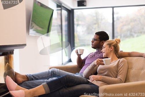 Image of Young multiethnic couple  in front of fireplace