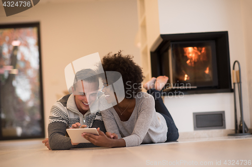 Image of multiethnic couple using tablet computer on the floor