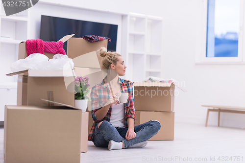 Image of woman with many cardboard boxes sitting on floor