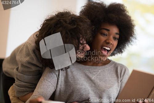 Image of multiethnic couple hugging in front of fireplace