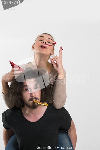 Image of couple in party hats blowing in whistle