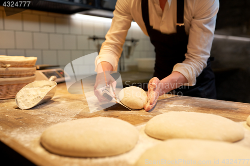 Image of baker portioning dough with bench cutter at bakery