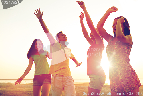 Image of smiling friends dancing on summer beach