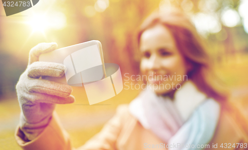 Image of woman taking selfie by smartphone in autumn park