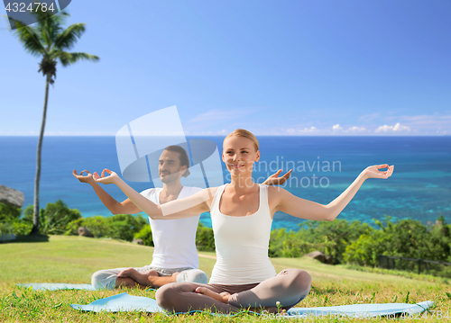 Image of couple doing yoga in lotus pose outdoors