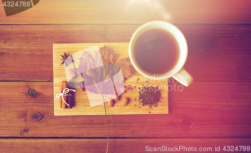 Image of cup of tea, maple leaf and almond on wooden board