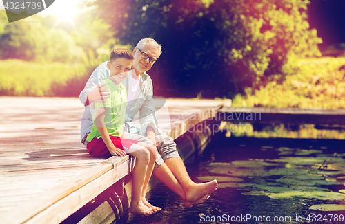 Image of grandfather and grandson sitting on river berth