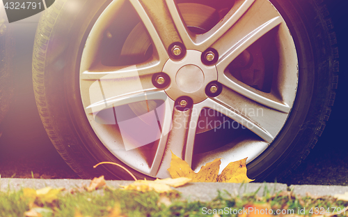 Image of close up of car wheel and autumn leaves