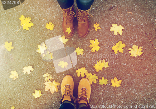 Image of couple of feet in boots and autumn leaves