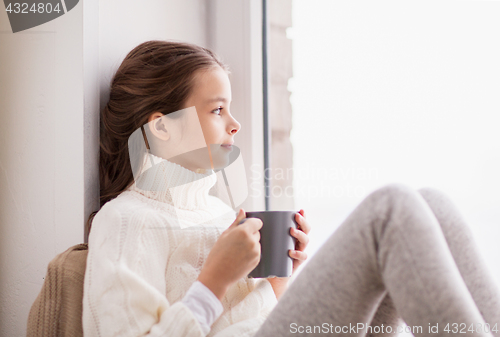 Image of girl with tea mug sitting at home window