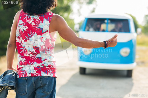 Image of man hitchhiking and stopping minivan car