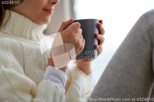 Image of girl with tea mug sitting at home window