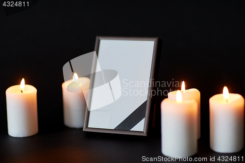 Image of black ribbon on photo frame and candles at funeral