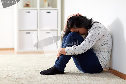 Image of unhappy woman crying on floor at home