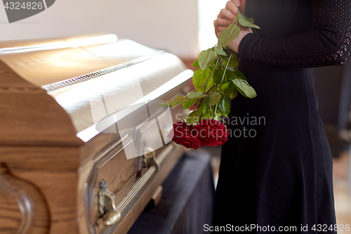 Image of woman with red roses and coffin at funeral