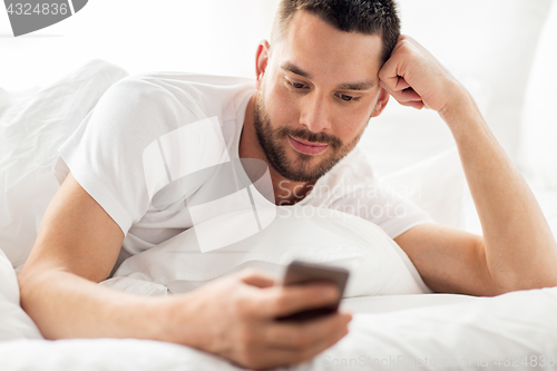 Image of close up of man with smartphone in bed in morning