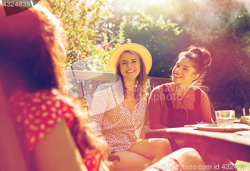 Image of happy friends having dinner at summer garden