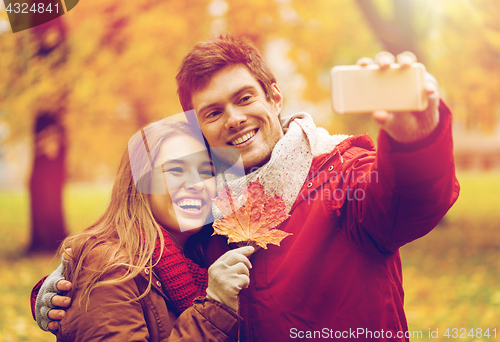 Image of couple taking selfie by smartphone in autumn park