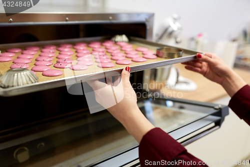 Image of chef with macarons on oven tray at confectionery