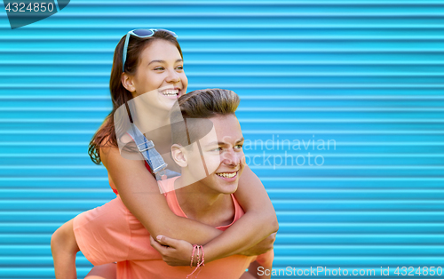 Image of happy teenage couple having fun over blue