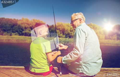 Image of grandfather and grandson fishing on river berth