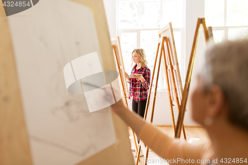 Image of student girl with easel painting at art school