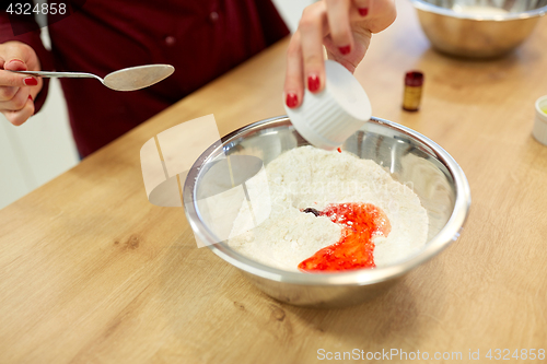 Image of chef hands adding food color into bowl with flour