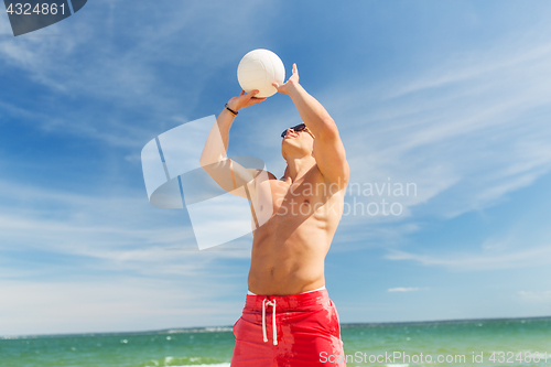 Image of young man with ball playing volleyball on beach