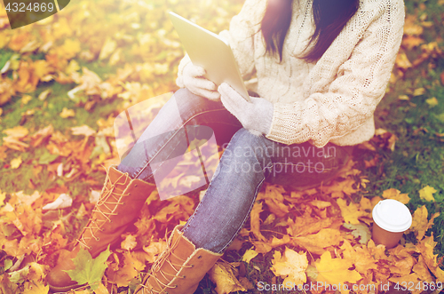 Image of woman with tablet pc and coffee in autumn park